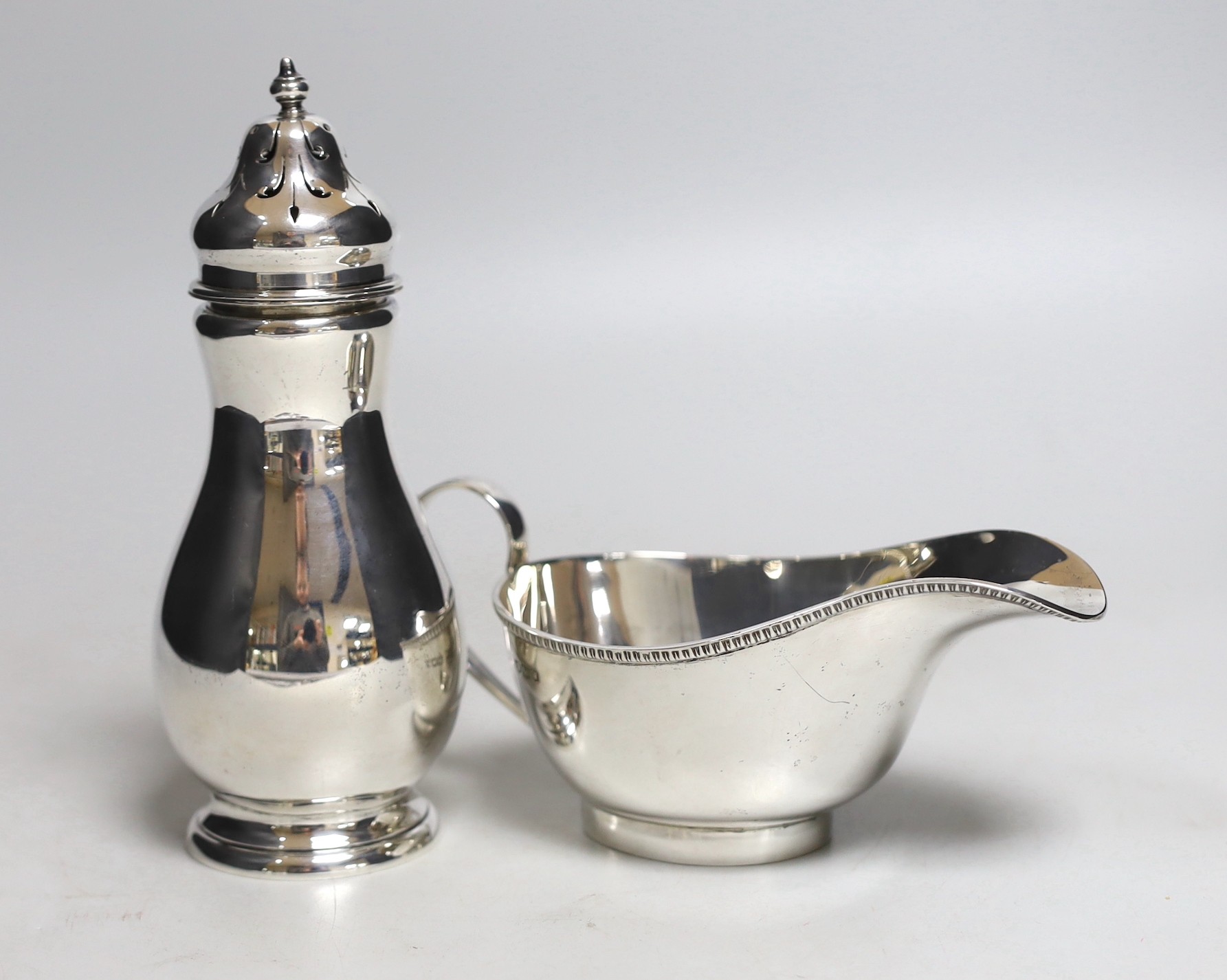 A George V silver sugar caster, Birmingham, 1932, 16.8cm and a silver sauce boat, 10.2oz.